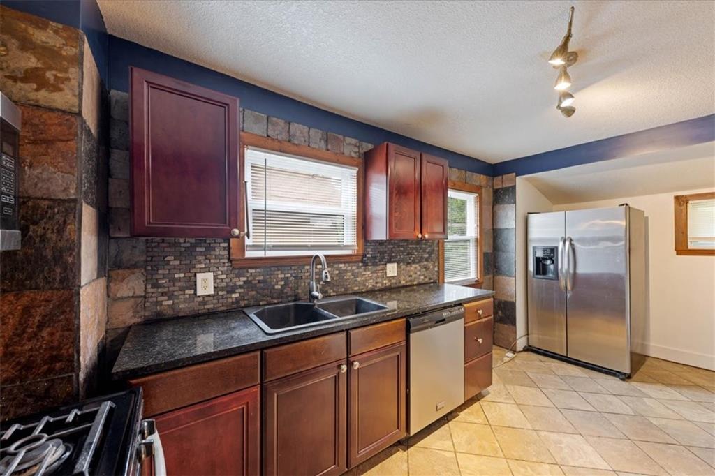 Kitchen with reddish wood cabinets, dark countertops, and stainless steel appliances.