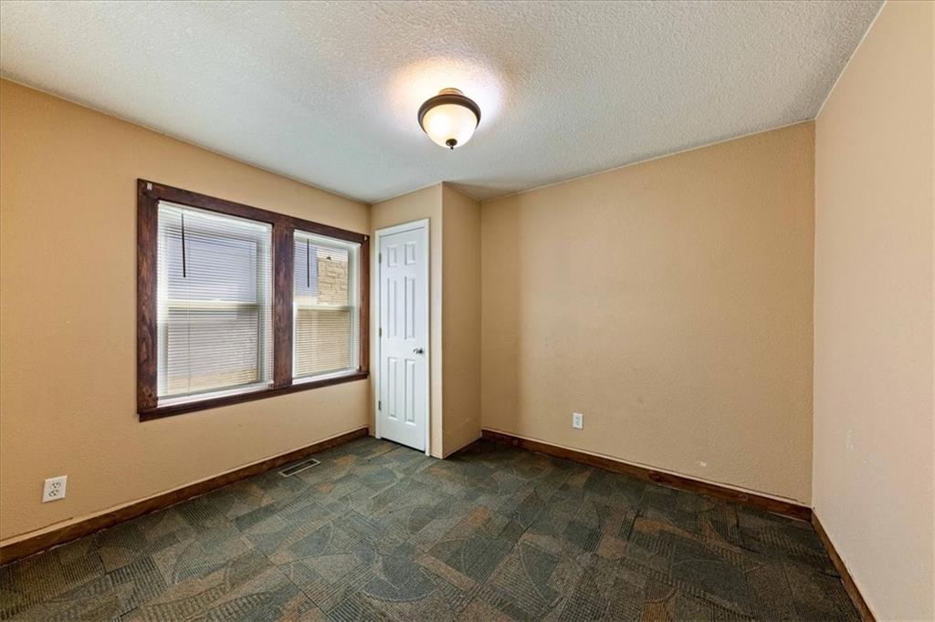 Empty bedroom with two windows, patterned carpet, and a white closet door.