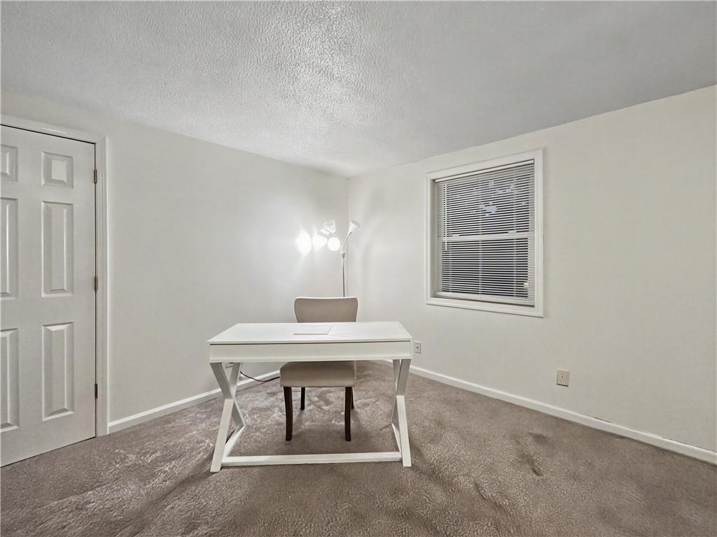 Small home office with a white desk, beige chair, and window with blinds.