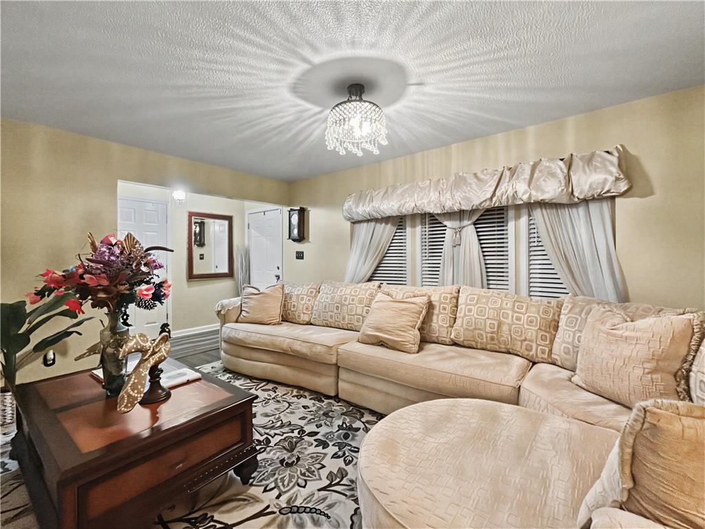 Living room with a beige sectional, patterned rug, and crystal chandelier.