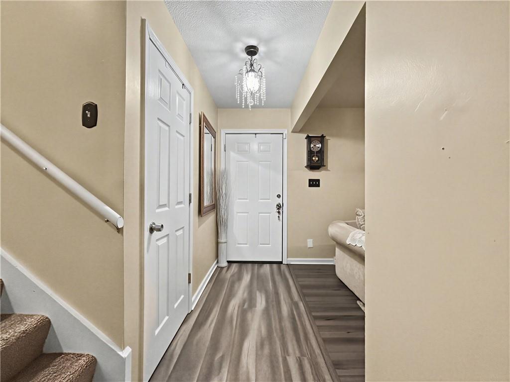 Entry hallway with gray flooring, white front door, chandelier, and stairs.