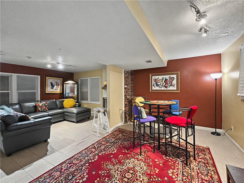 Living and dining area with a leather sectional and colorful table on a red patterned rug.