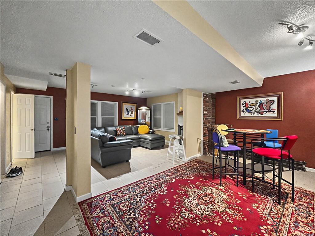 Open living and dining area with a gray sectional and colorful chairs around a table.