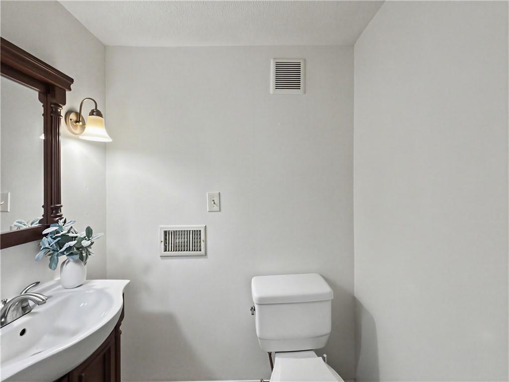 Bathroom with a white toilet, dark wood vanity, and framed mirror.