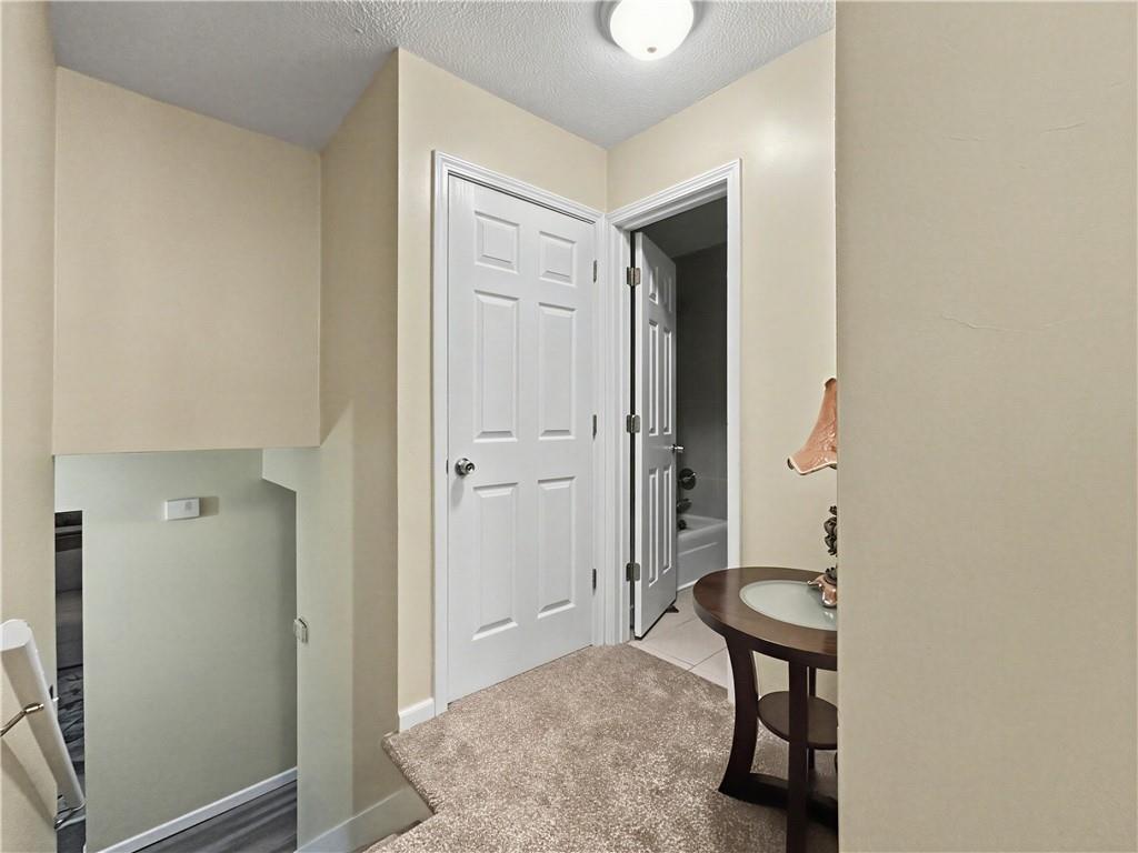 Carpeted hallway with white paneled doors and a small sink table beside an open bathroom.
