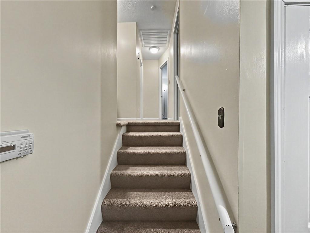 Carpeted staircase with a white handrail leading to an upstairs hallway.