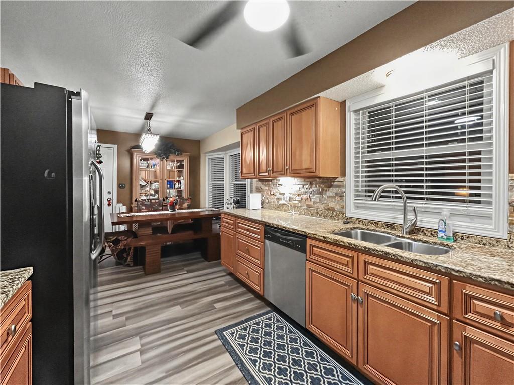 Kitchen with warm wood cabinets, granite counters, and a dining nook with a wooden table.