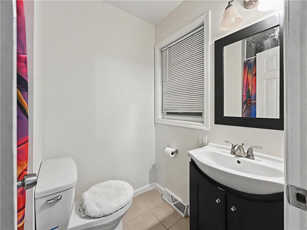 Bathroom with a dark vanity, white sink, black-framed mirror, and colorful shower curtain.