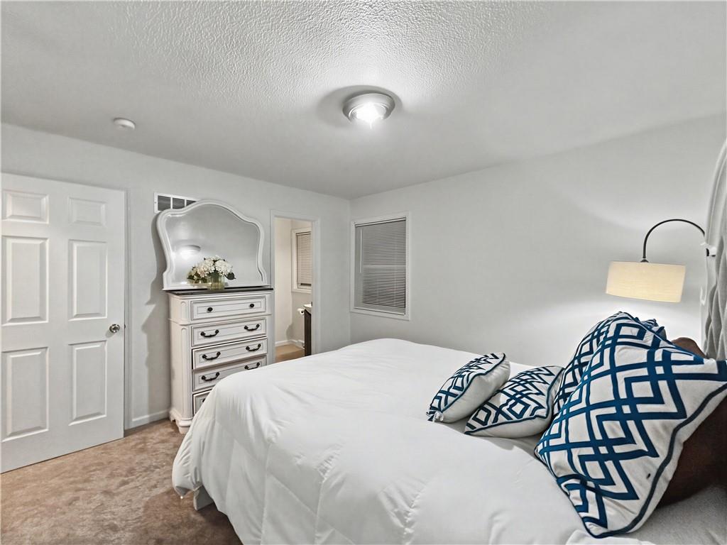 Bedroom with a white bed, blue patterned pillows, and a mirrored dresser.