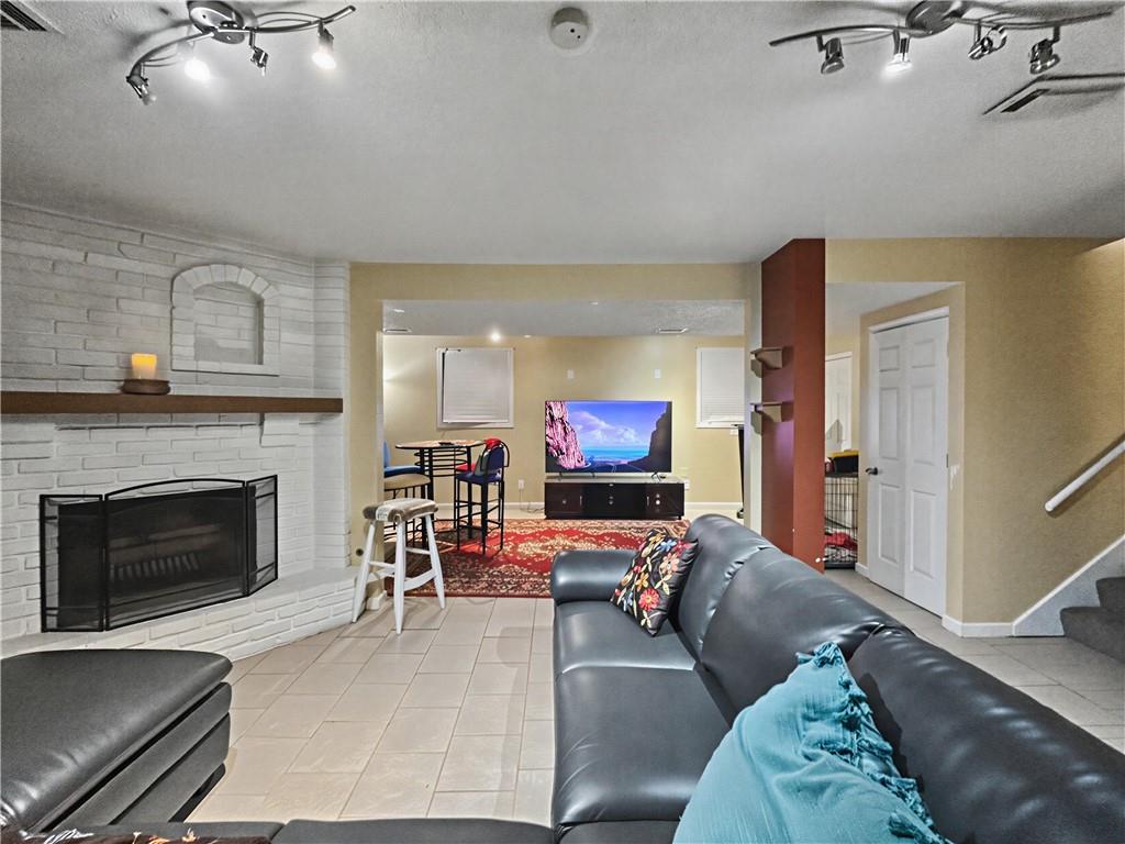 Living room with a white brick fireplace, gray sectional, and television in the rear sitting area.