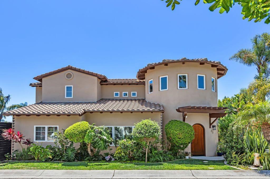 Mediterranean-style stucco home with a round tower, tile roof, and landscaped front yard.
