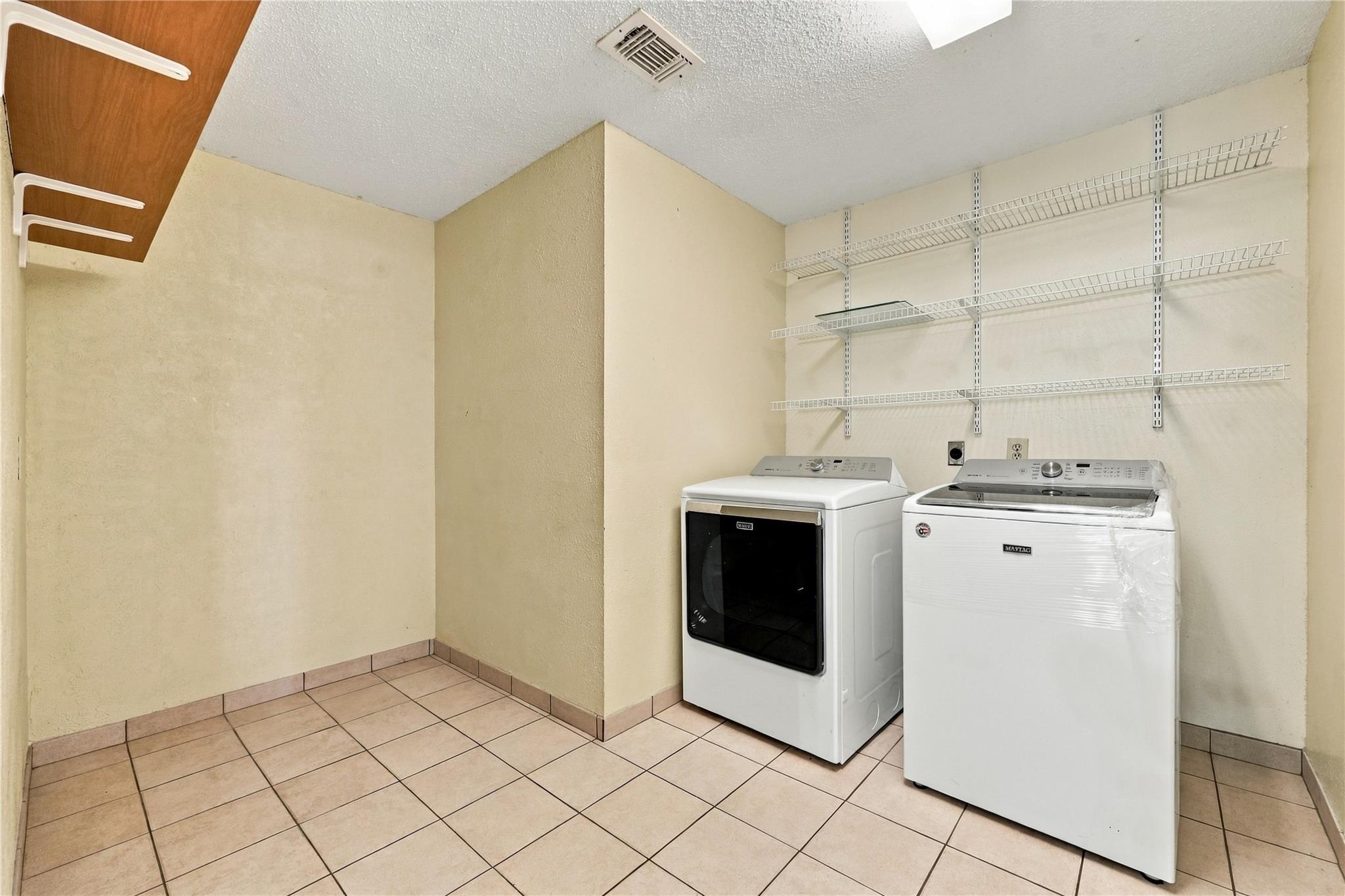 Laundry room with washer, dryer, and wall-mounted wire shelving.