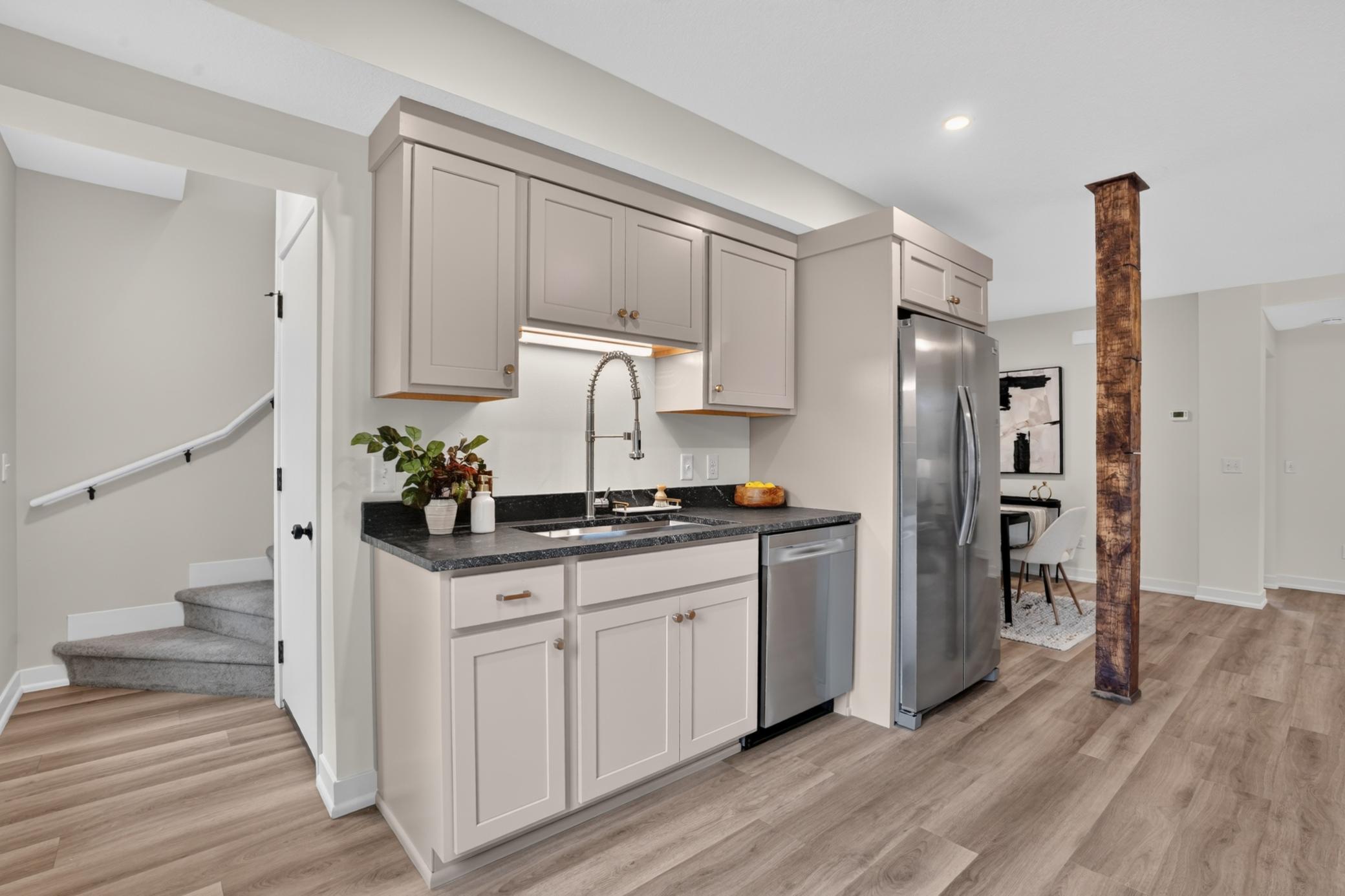 Kitchen with light gray cabinets, dark countertops, stainless steel appliances, and a wood post beside the dining area.