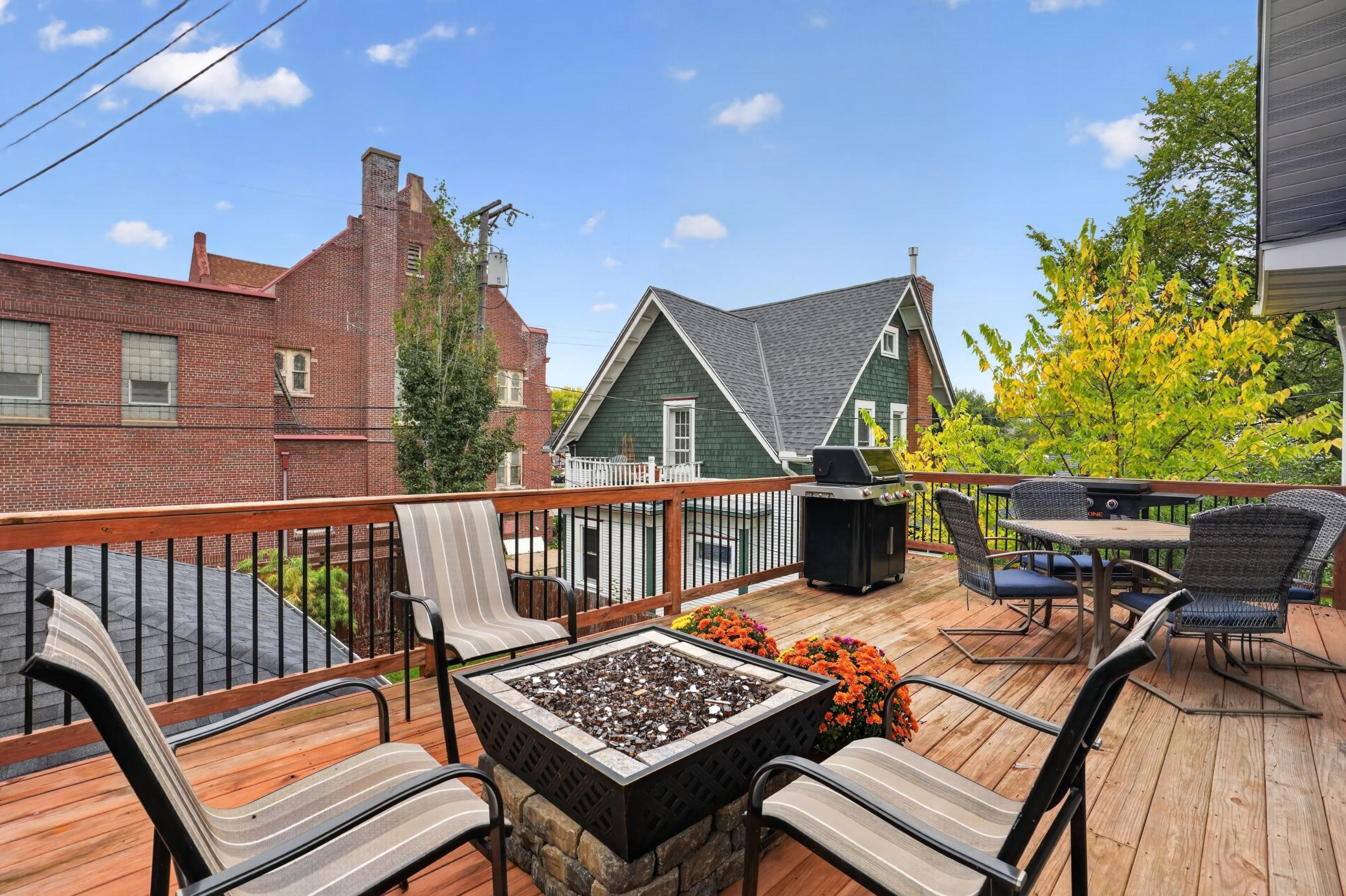 Rooftop deck with a square fire pit, lounge chairs, dining table, and grill.