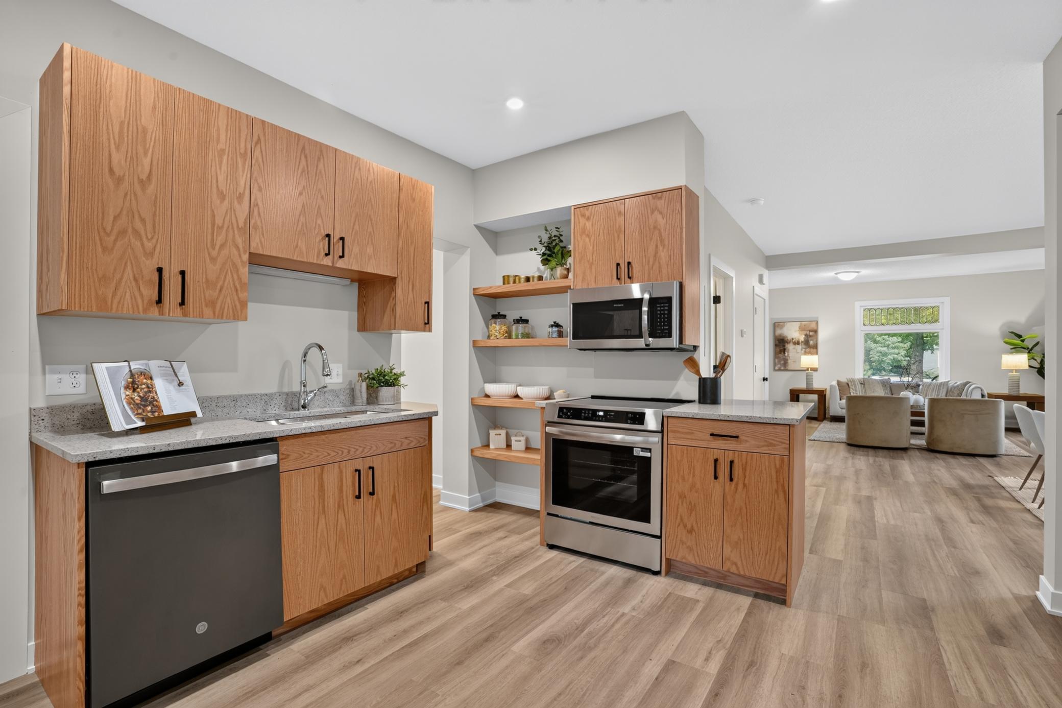 Open-plan kitchen with wood cabinets, stainless steel appliances, and a view into the living area.