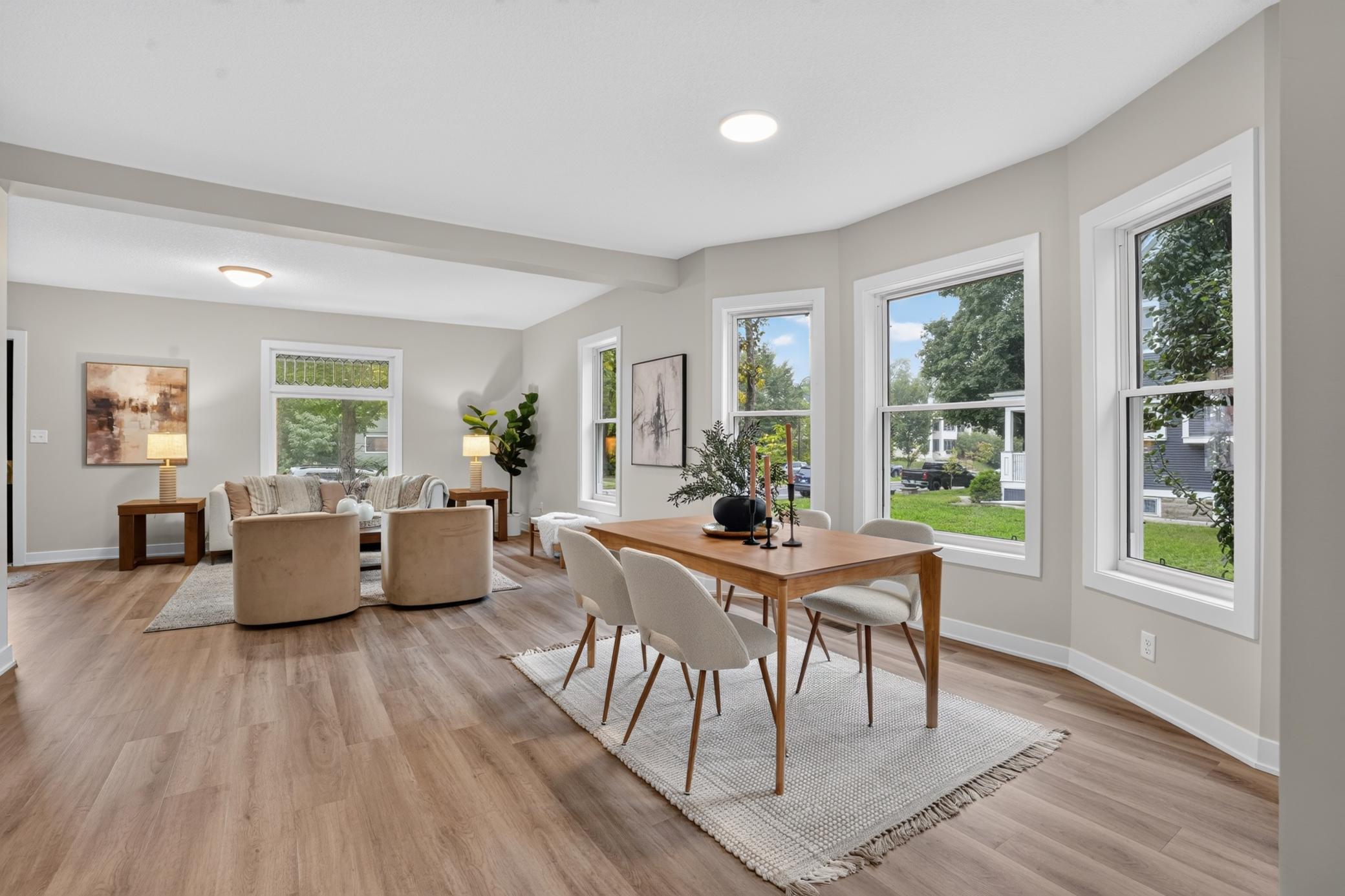 Open-plan living and dining room with a wooden dining table, cozy seating, and large windows.