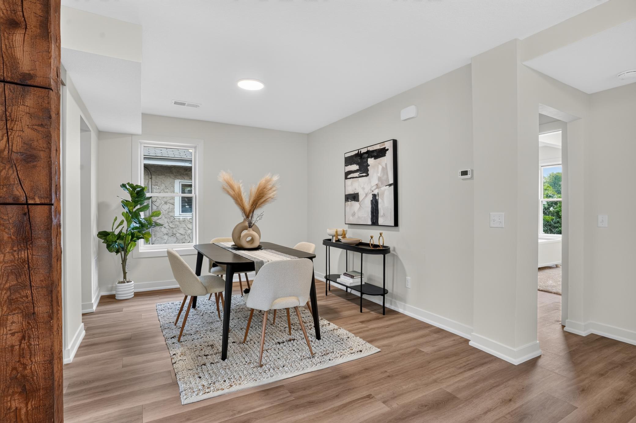 Staged dining room with a dark table and upholstered chairs on a textured rug.