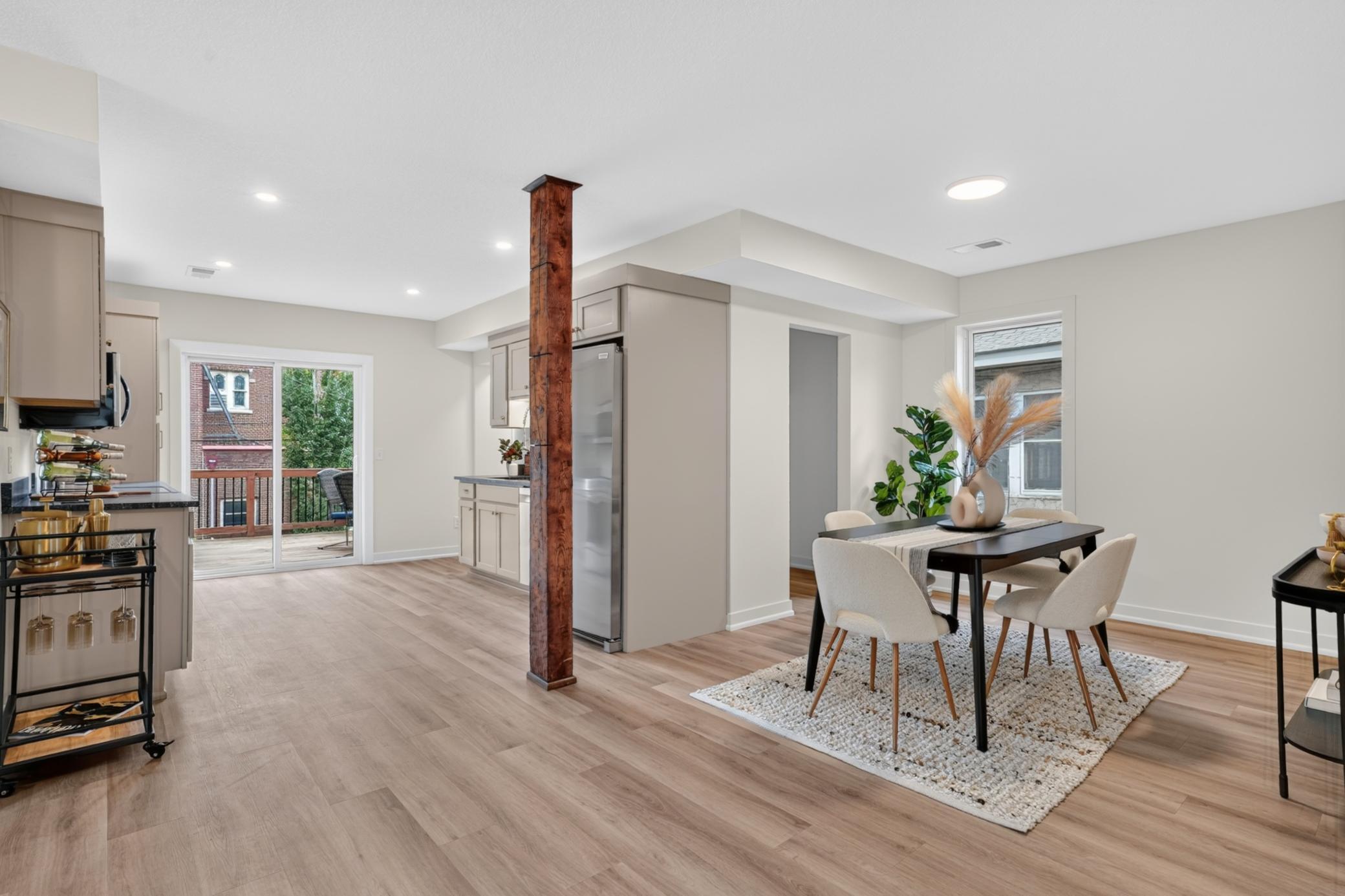 Open kitchen and dining area with a rustic wood post, light floors, and sliding doors to a deck.