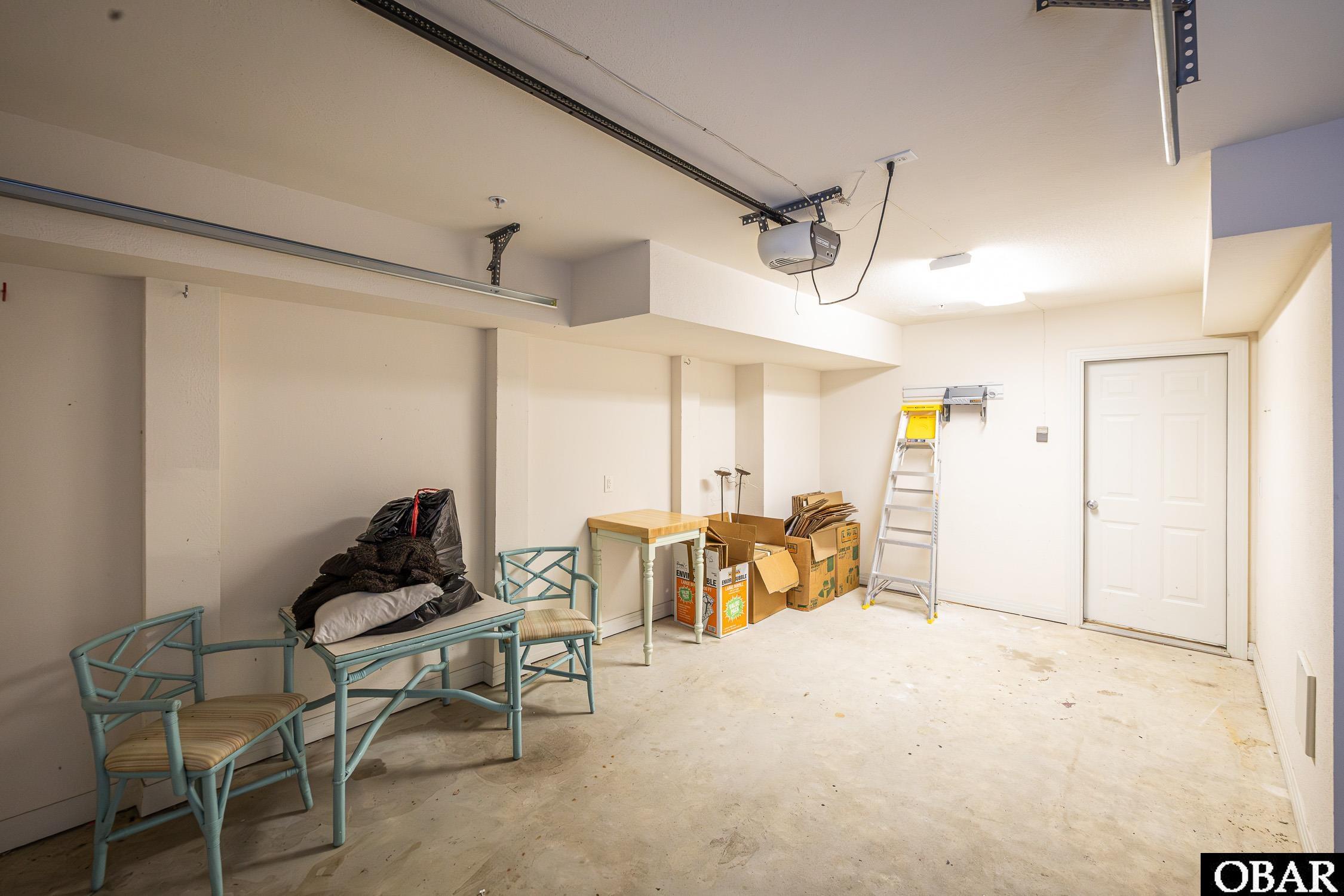 Garage with storage boxes, a ladder, and chairs beside the interior door.
