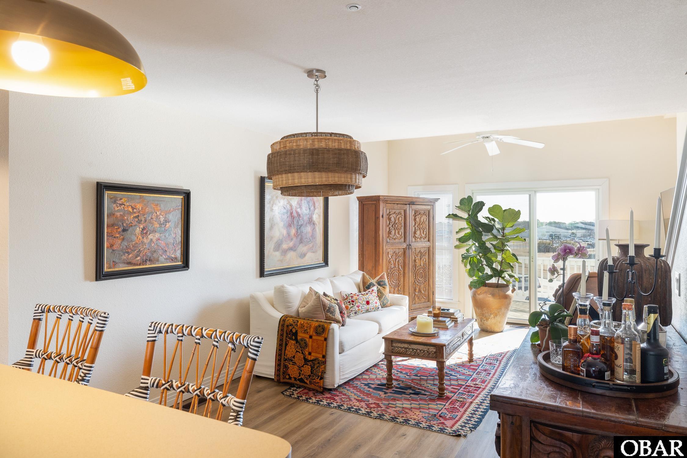 Bright furnished living room with a white sofa, patterned rug, carved cabinet, and sliding glass doors.