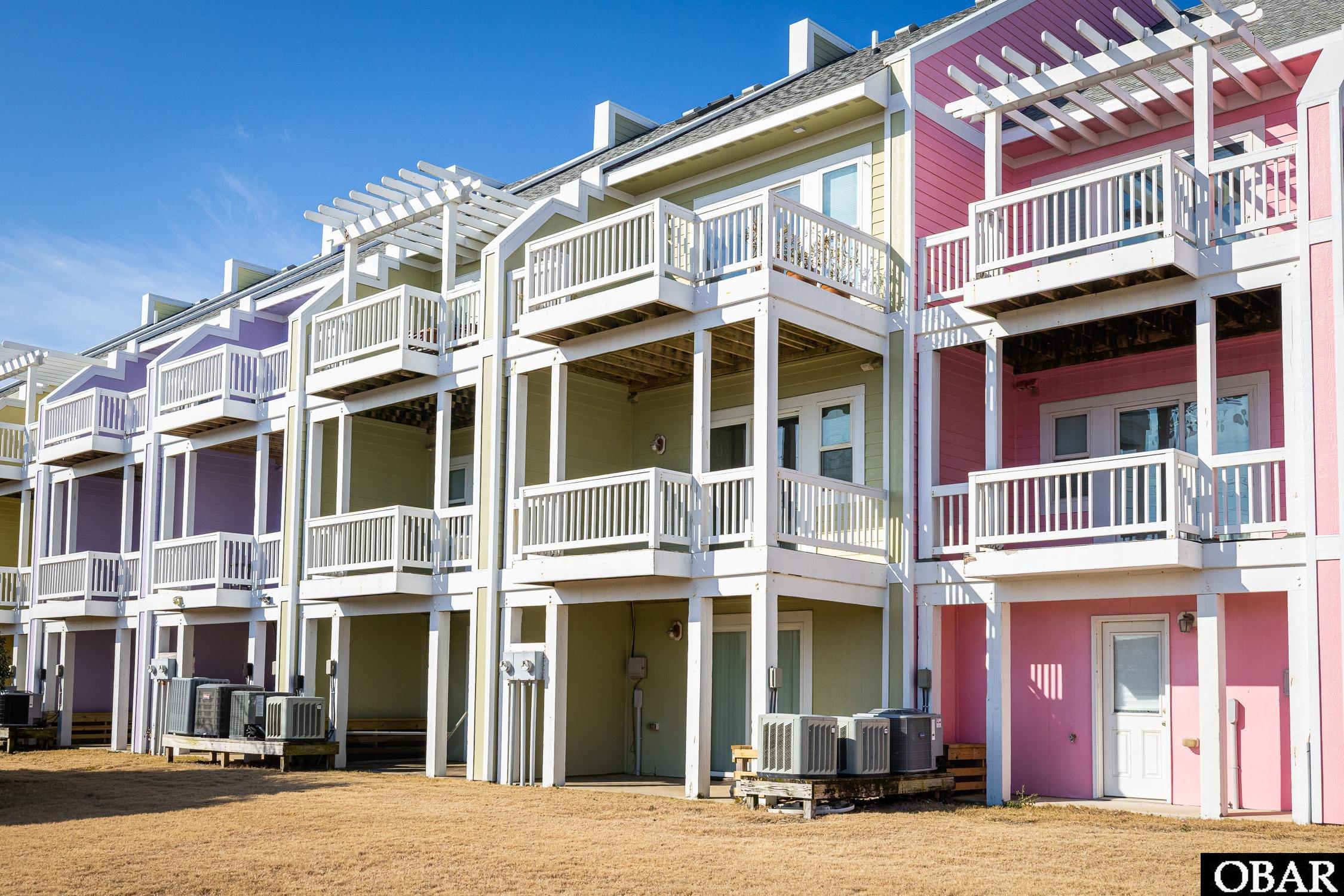 Multistory condominium building with pastel siding, white balconies, and pergolas.