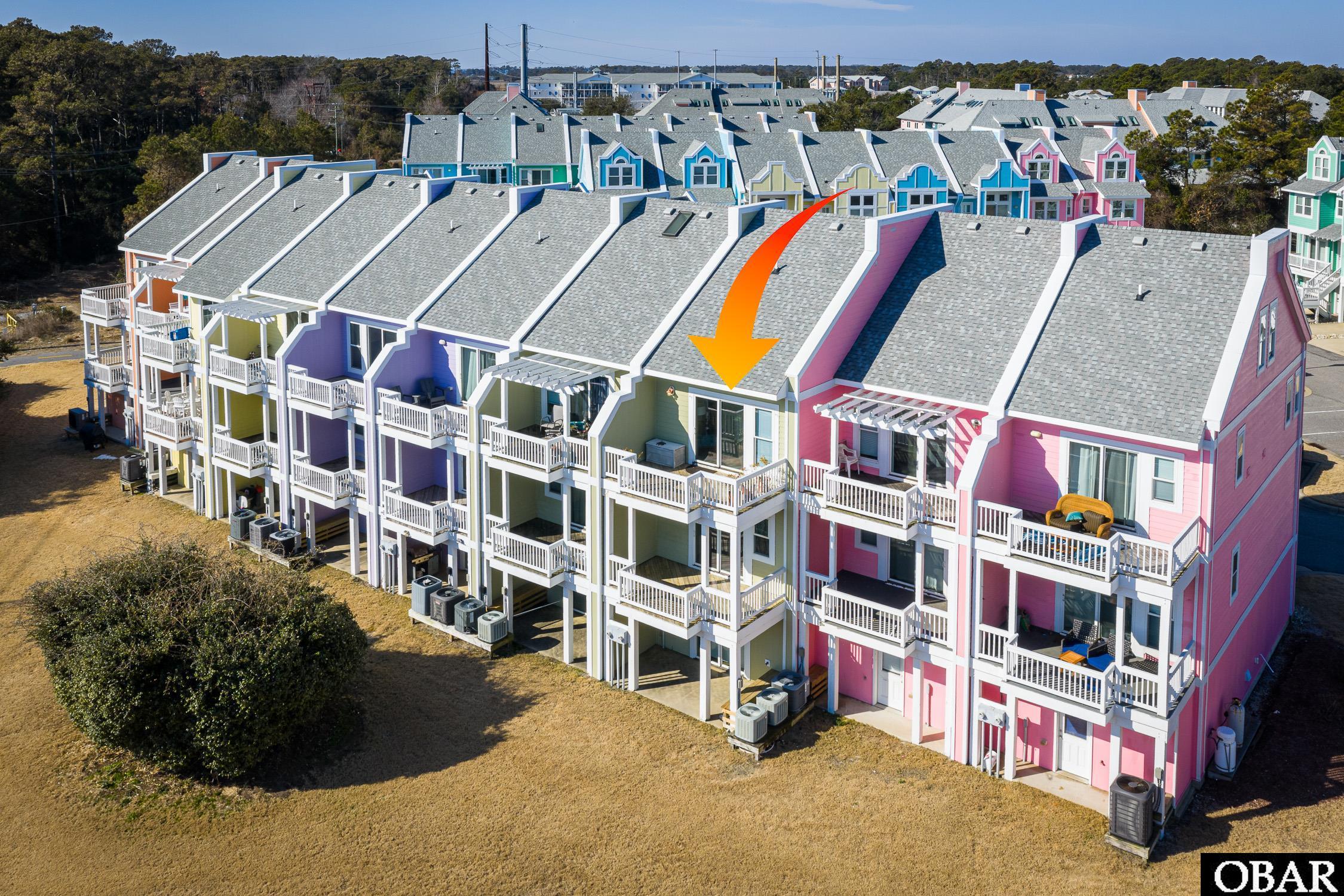 Aerial view of colorful townhomes, with an orange arrow pointing to the green unit.