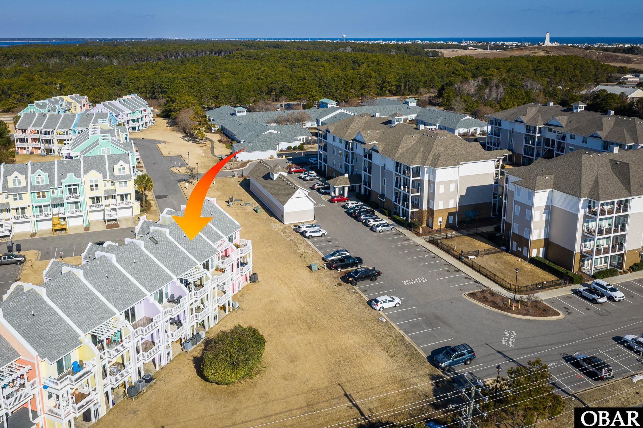 Aerial view of a condominium complex, with an orange arrow pointing to a building and ocean beyond.