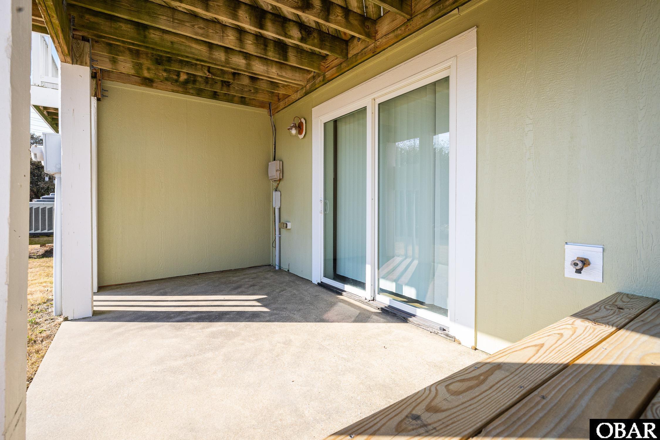 Covered concrete patio with sliding glass doors and a wooden ceiling.