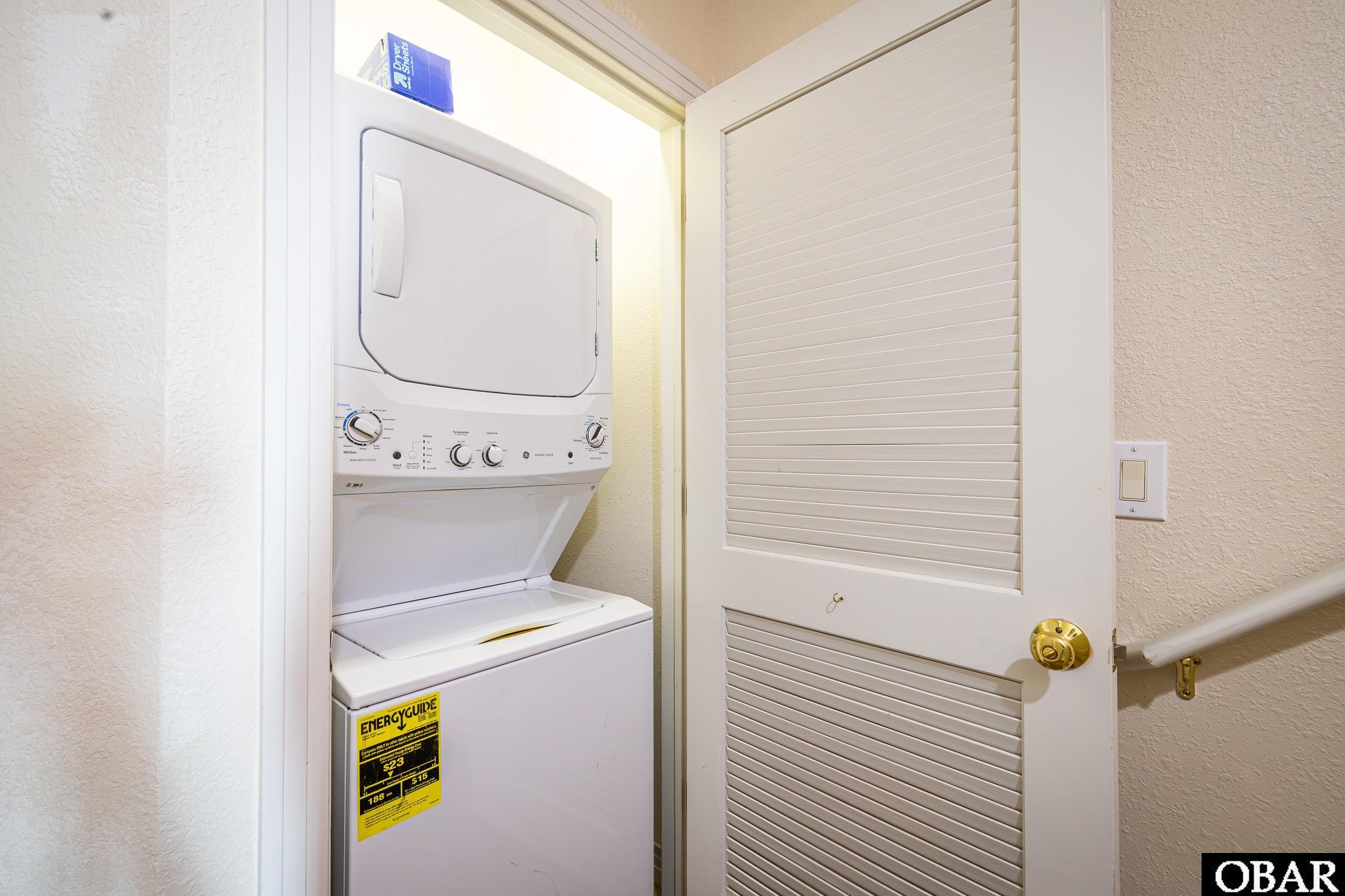 Laundry closet with a stacked washer and dryer behind a louvered door.