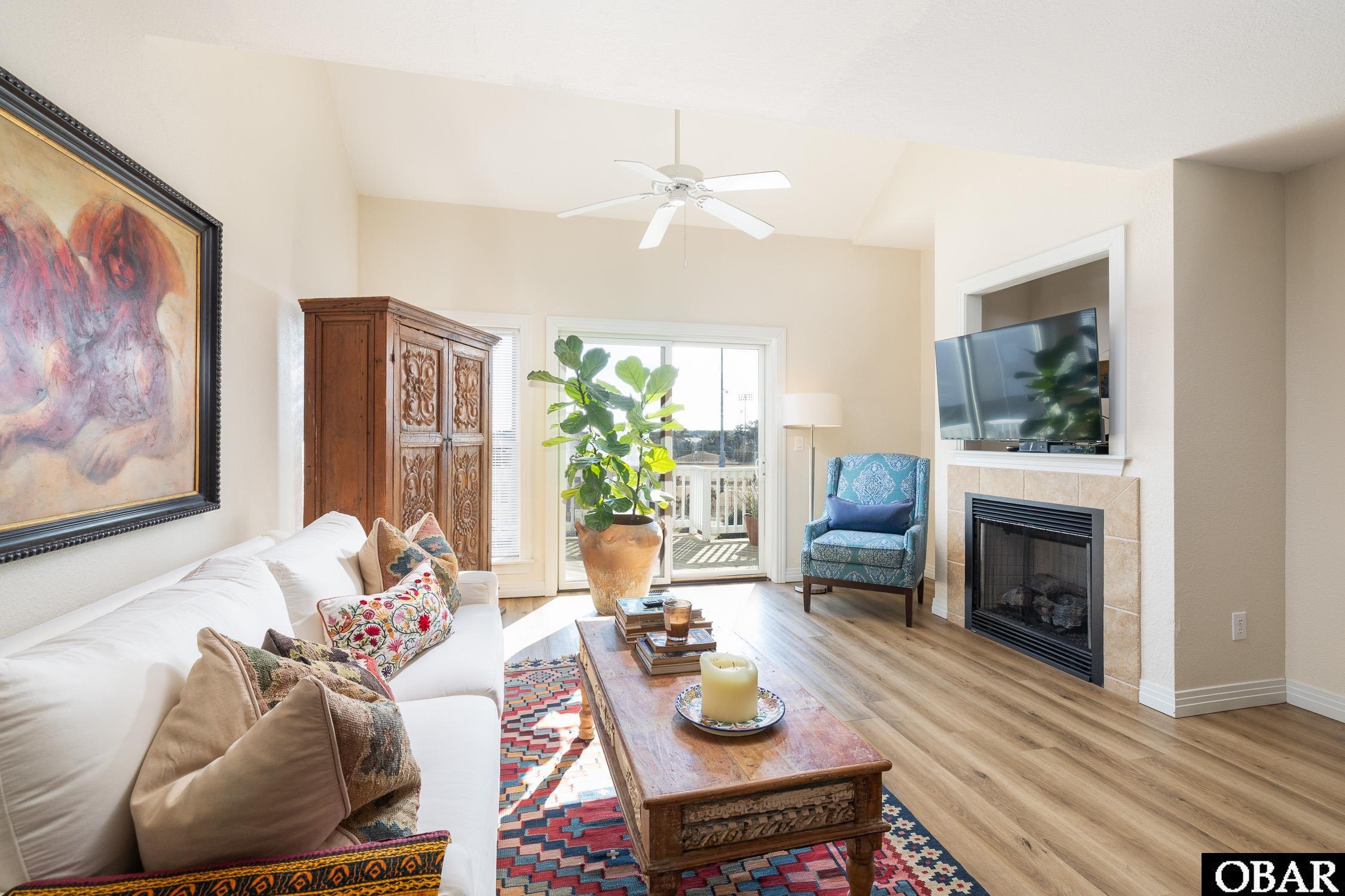 Living room with a white sofa, carved wood coffee table, fireplace, and sliding doors to a balcony.