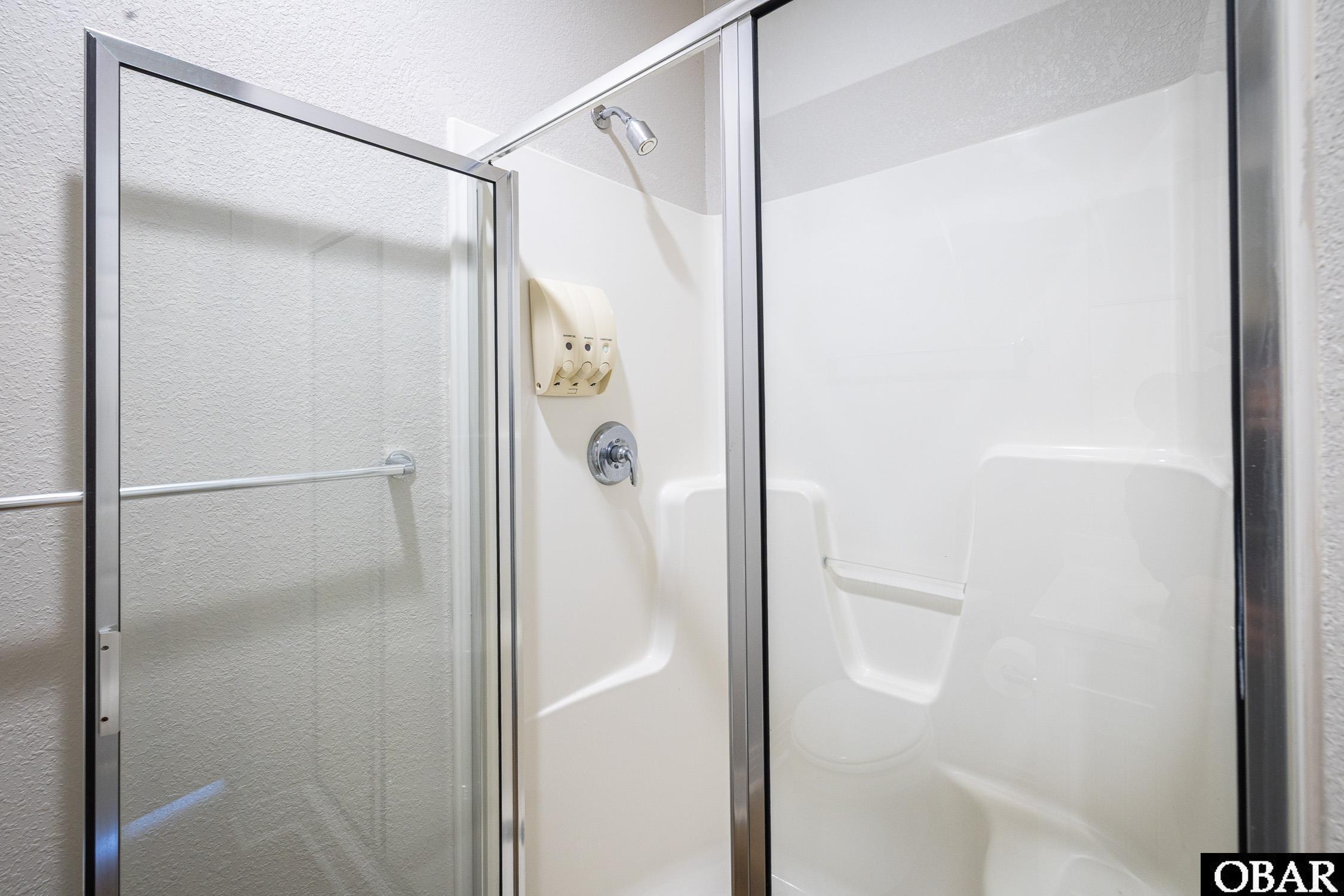 Bathroom shower with a glass enclosure, built-in seat, and wall-mounted controls.