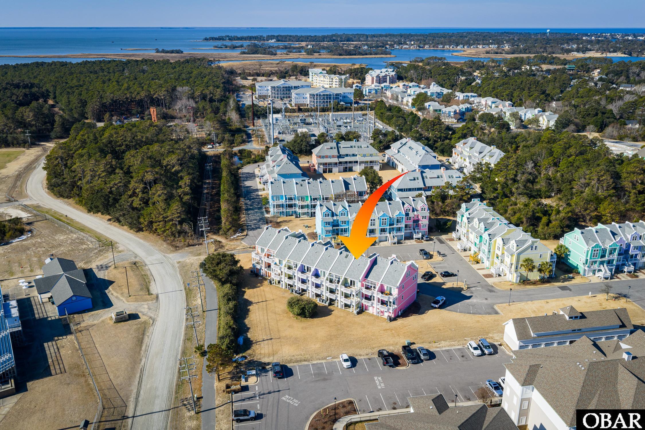 Aerial view of colorful coastal townhomes, with an orange arrow marking the pink end unit.