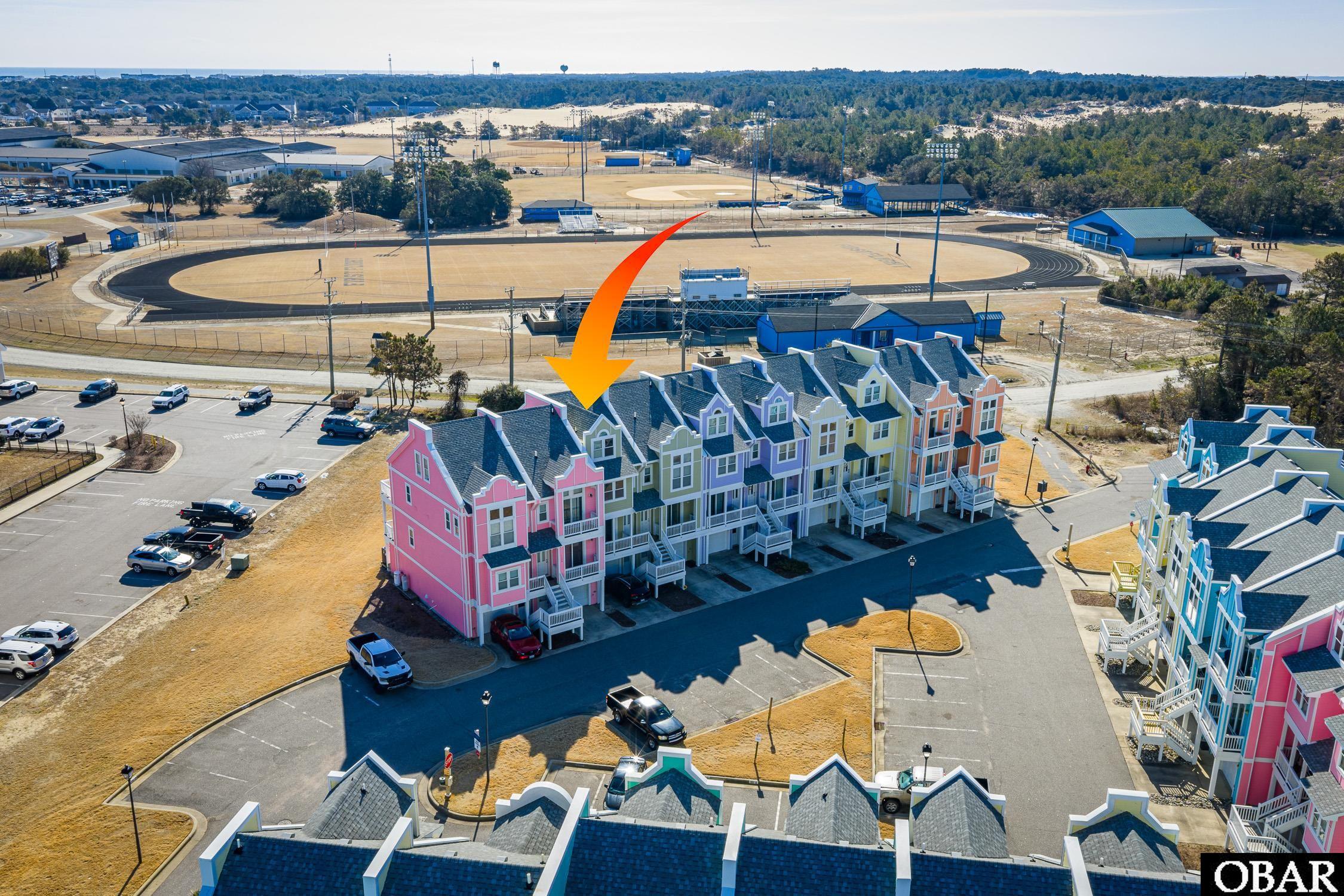 Aerial view of colorful townhomes, with an orange arrow pointing to the featured unit.