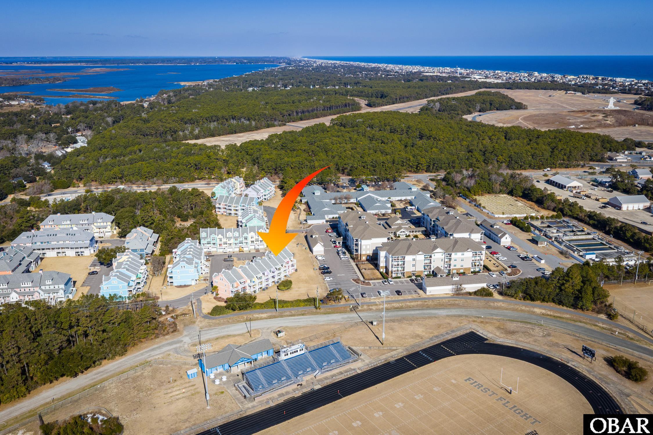 Aerial view of the townhouse complex, marked by an orange arrow, with water and a track nearby.