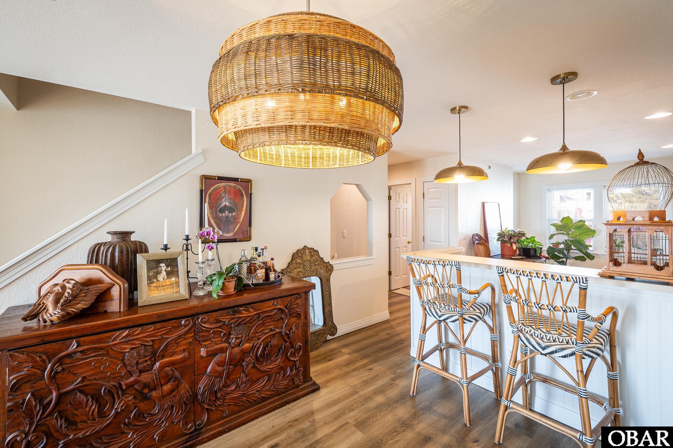 Furnished kitchen and dining area with woven pendant lights, a white island, and a carved wood sideboard.