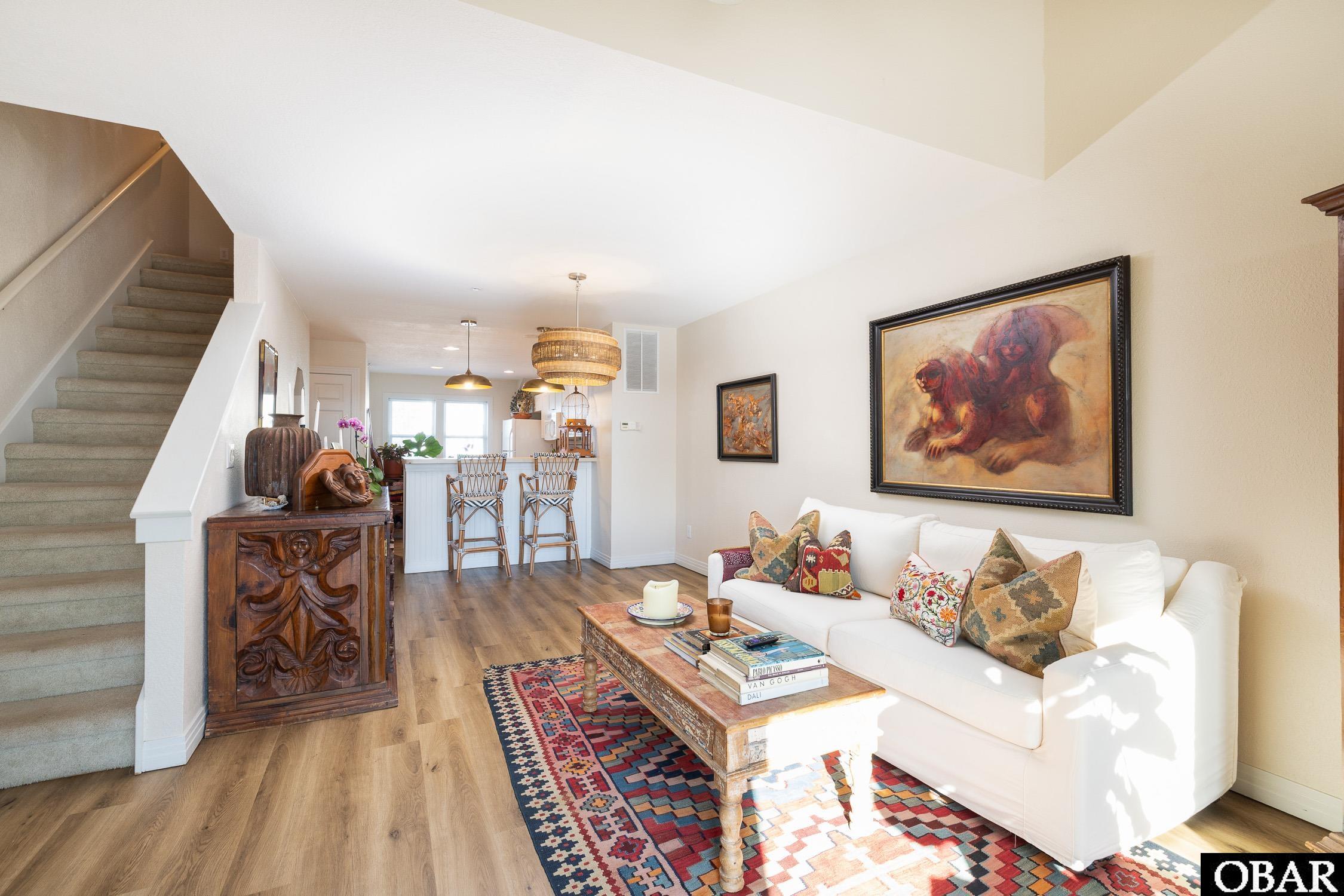 Living room with a white sofa, patterned rug, carved console, and staircase.