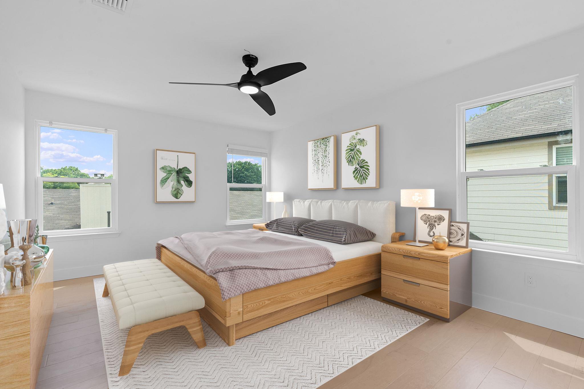 Staged bedroom with a wood platform bed, botanical wall prints, and three large windows.