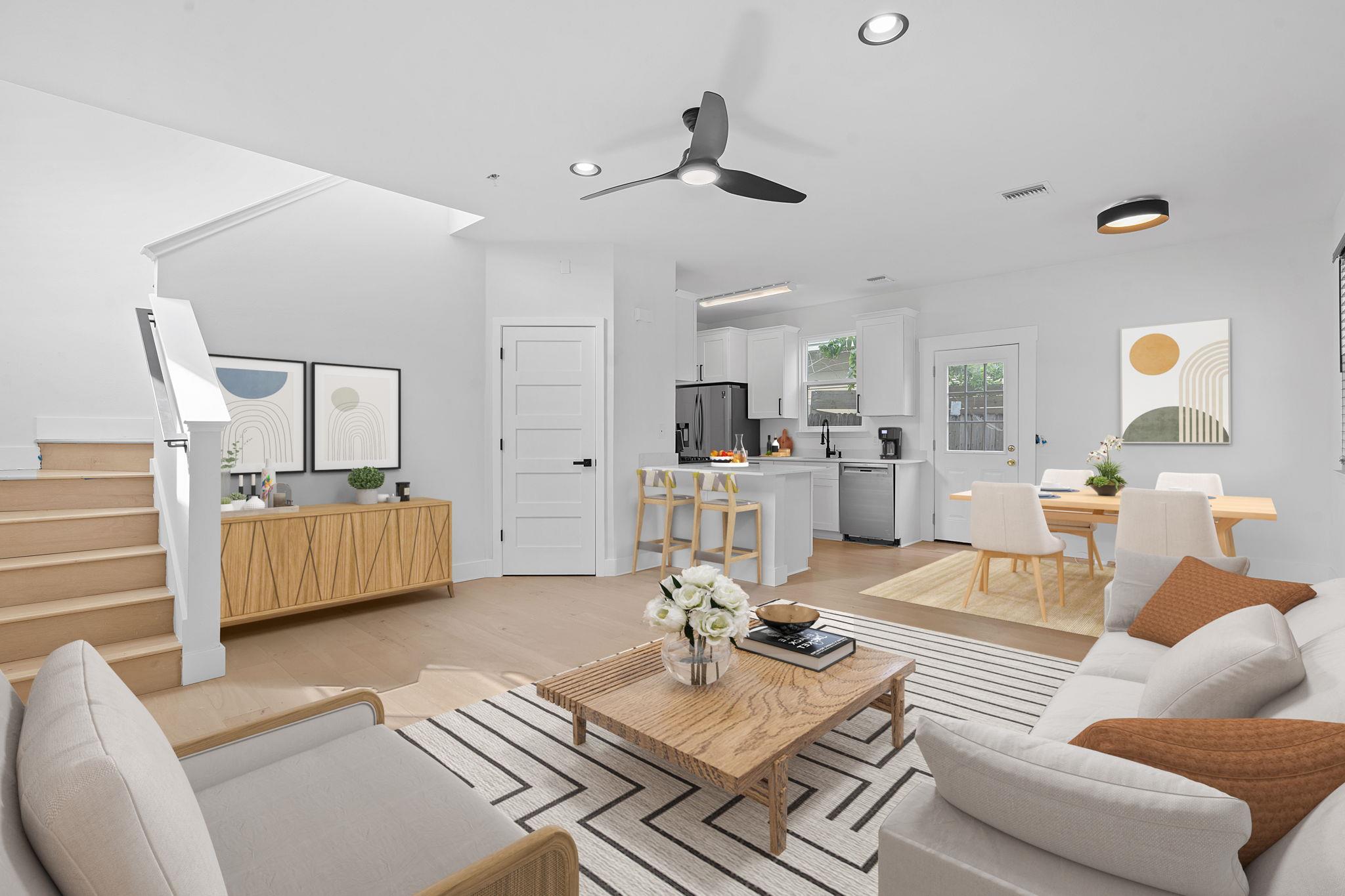 Open-plan living room, dining area, and kitchen with a wood coffee table and staircase.