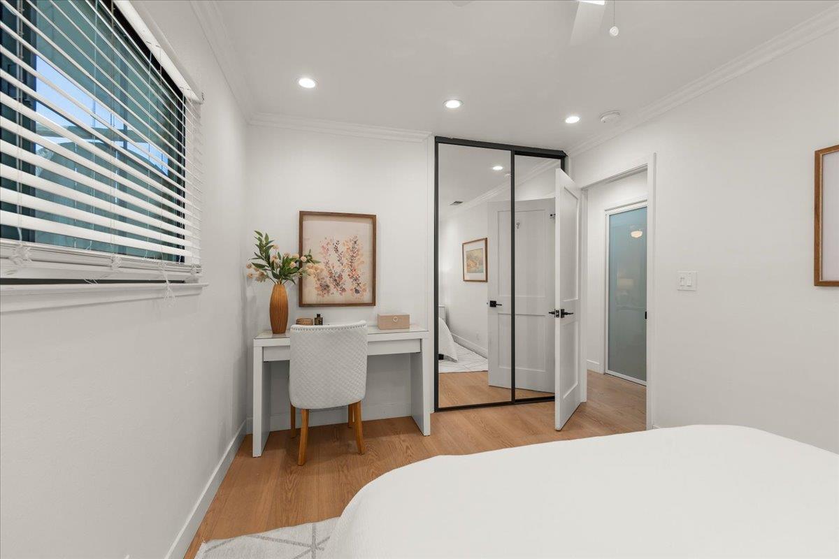 Furnished bedroom with a desk beside the window and mirrored closet doors.