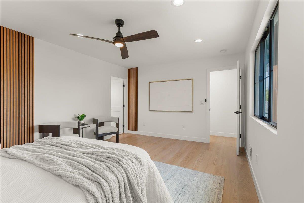 Staged bedroom with a white bed, wood slat accents, and a large window.