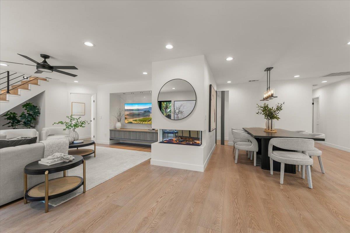 Open-plan living and dining room with a central glass fireplace and light wood floors.