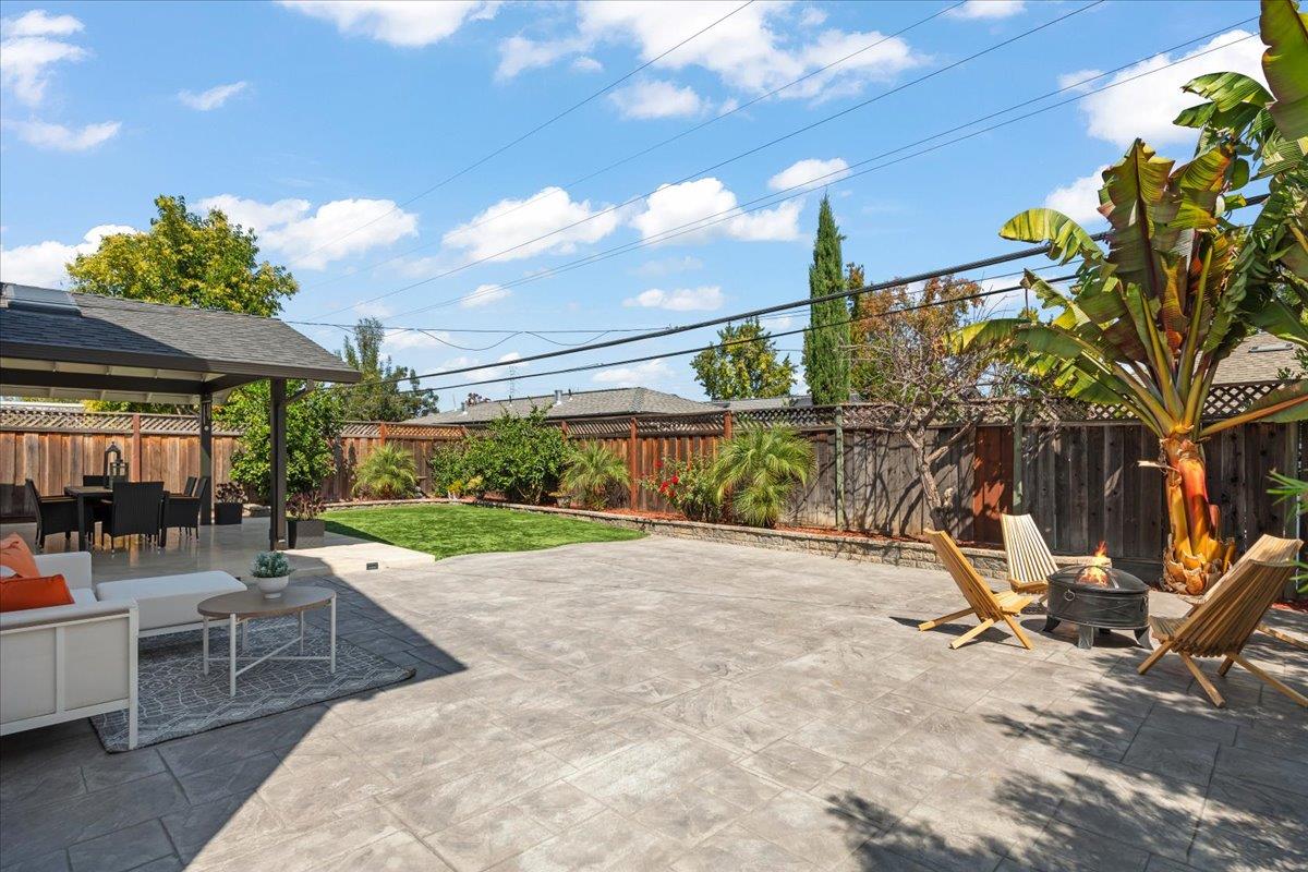 Backyard patio with outdoor seating, a small lawn, tropical plants, and a fire pit.