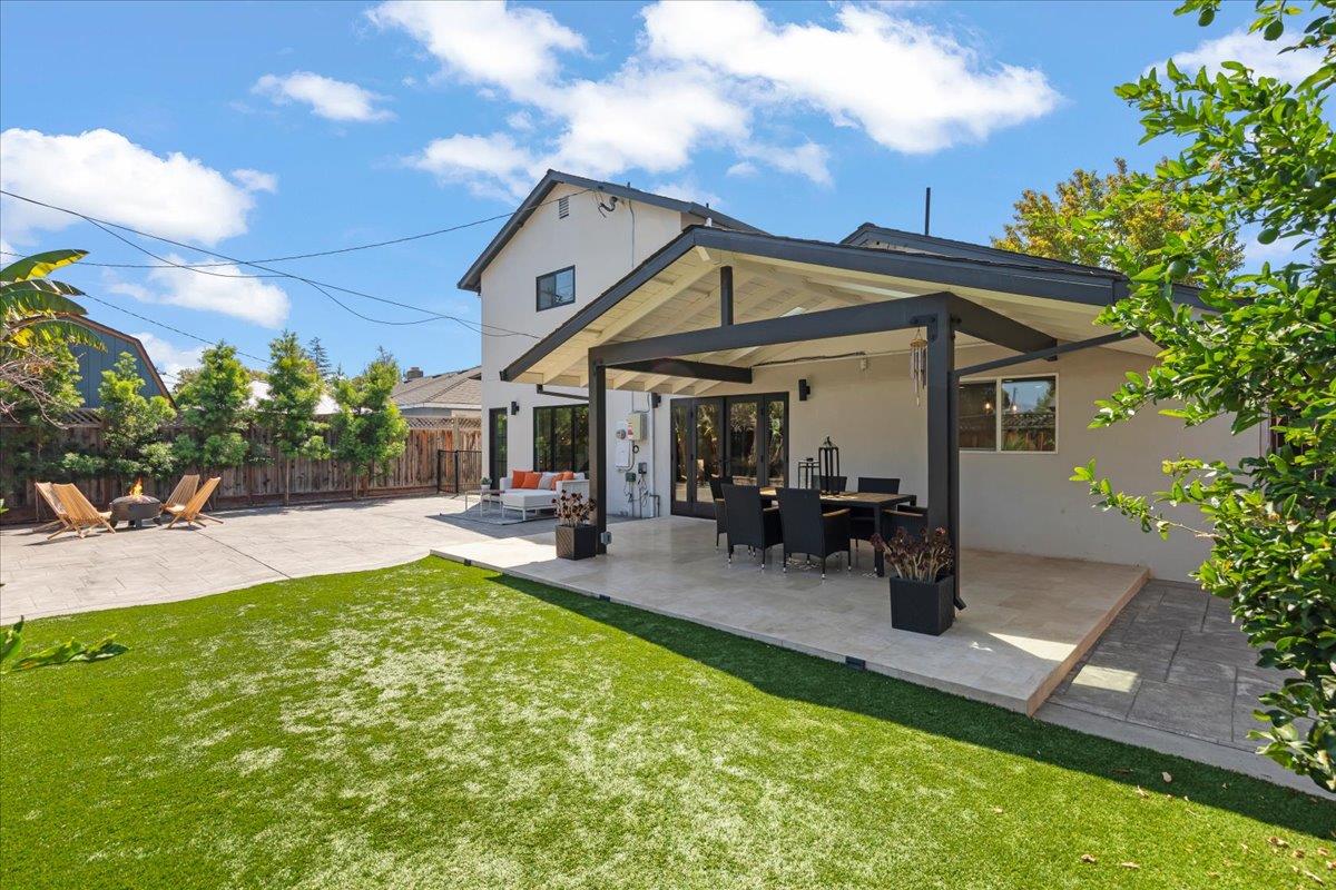 Home’s backyard with a covered patio, outdoor dining area, and lawn.