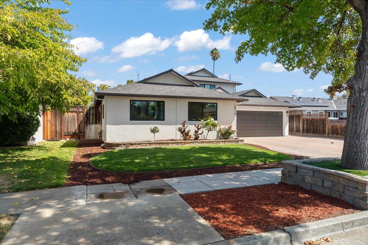 Single-story home with a two-car garage, landscaped lawn, and paved driveway.