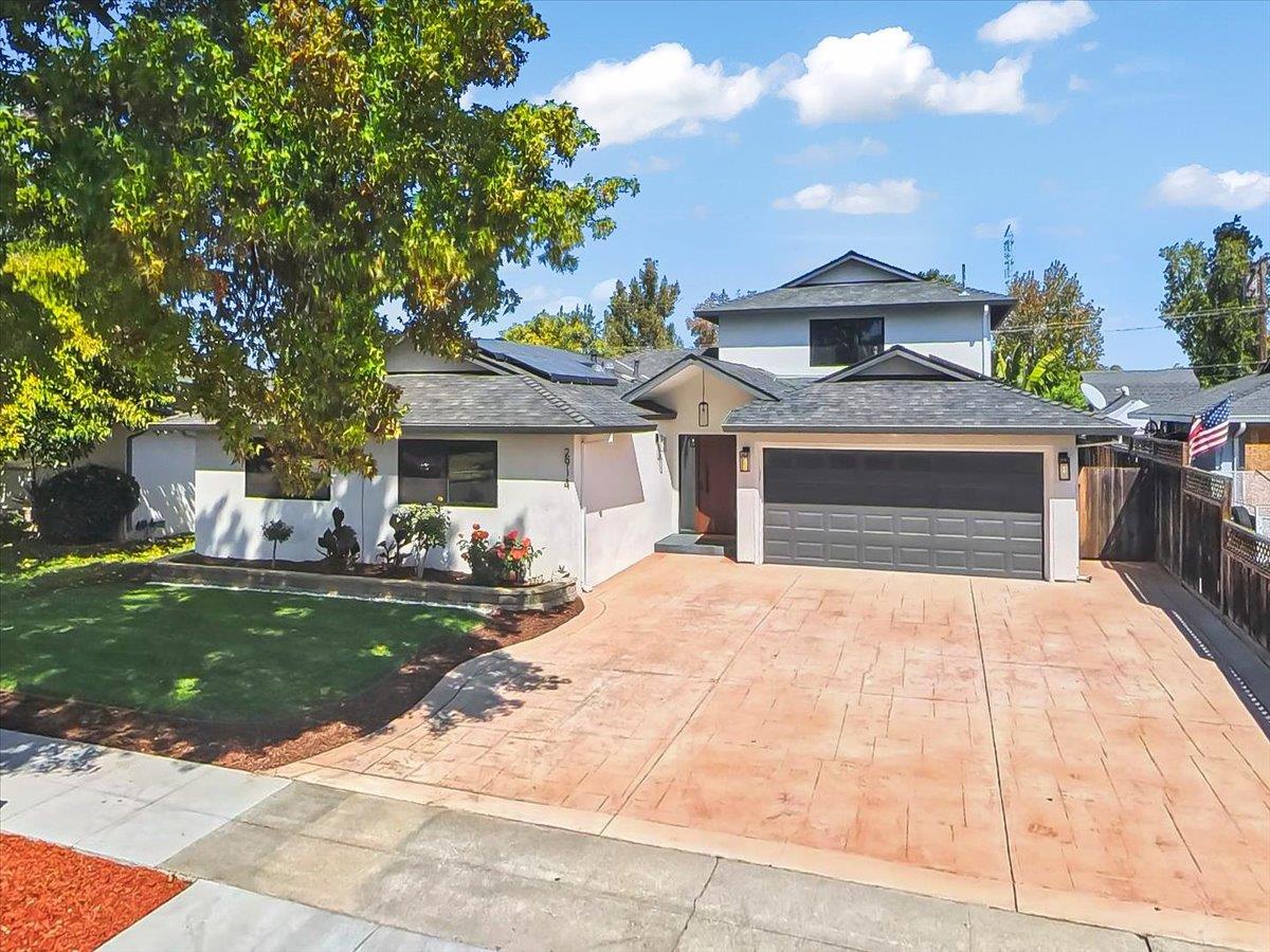 White two-story home with solar panels, a double garage, and a wide stamped-concrete driveway.