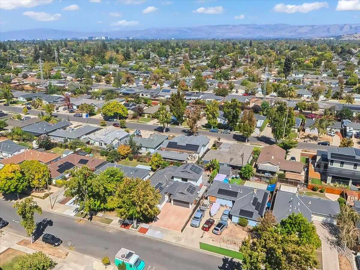 Aerial view of a residential neighborhood with tree-lined streets and distant hills.