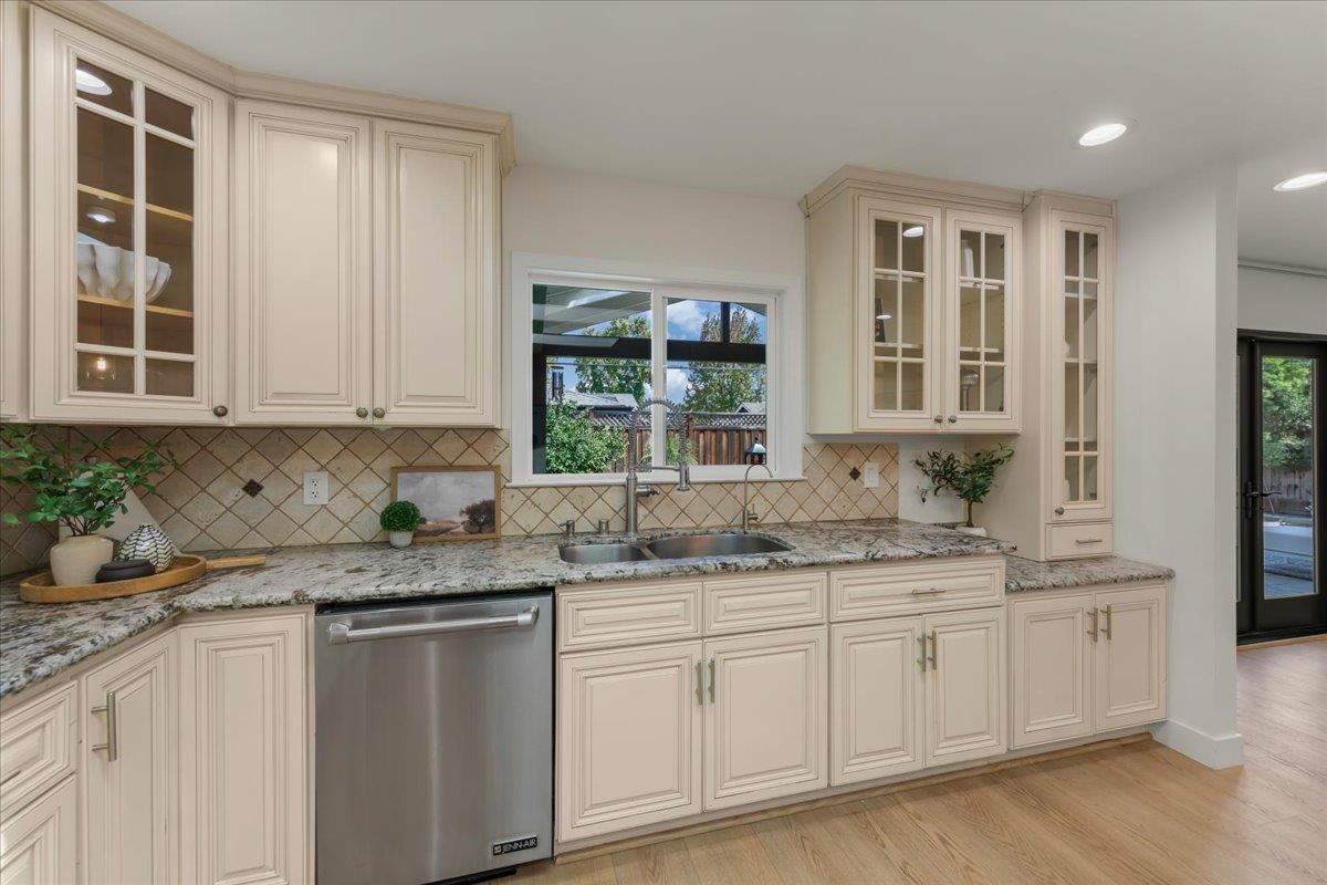Kitchen with cream cabinets, granite counters, and a sink beneath a window overlooking the yard.