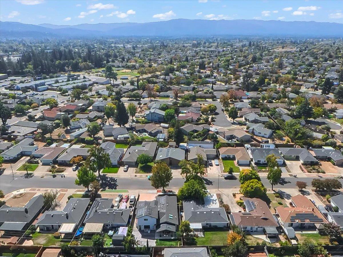 Aerial view of a San Jose neighborhood with homes, streets, and distant mountains.