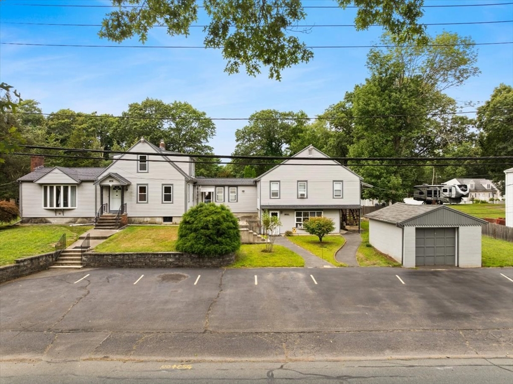 Light-sided property with landscaped lawn, paved parking, and detached garage