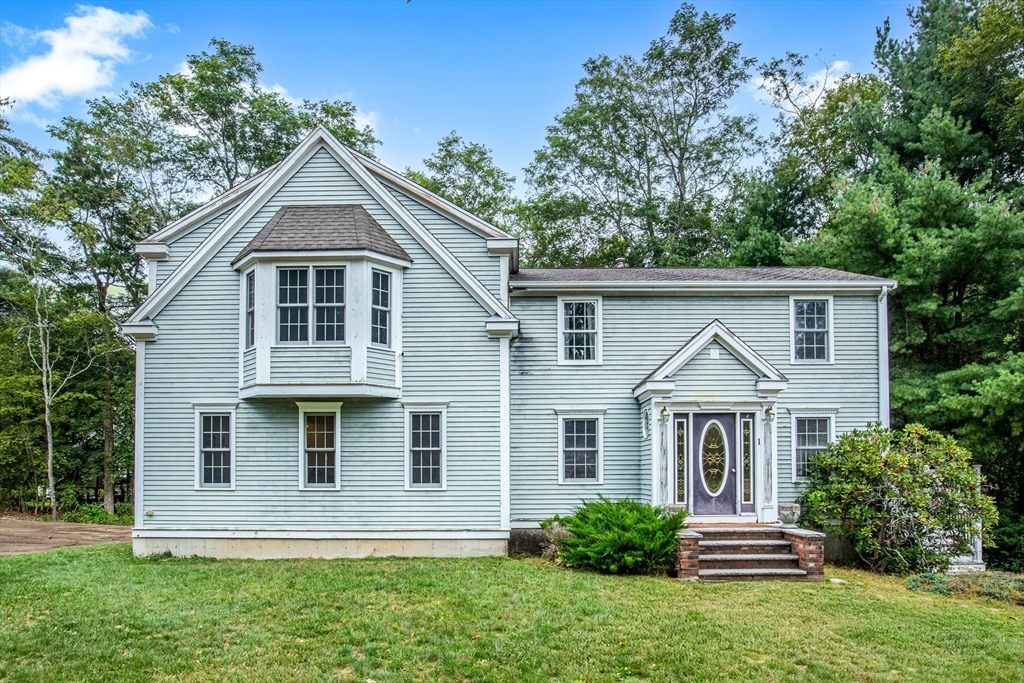 Two-story light-gray house with a prominent front gable, bay window, and brick entry steps.